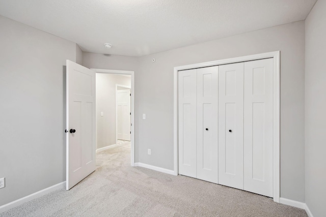 unfurnished bedroom featuring a closet, baseboards, and carpet flooring