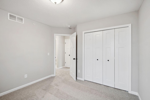 unfurnished bedroom with a closet, baseboards, light colored carpet, and visible vents