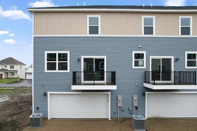 rear view of property featuring central AC, an attached garage, and a balcony