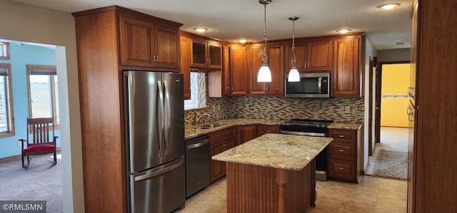 kitchen featuring light stone counters, a sink, stainless steel appliances, tasteful backsplash, and a center island