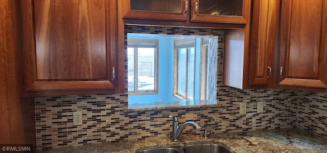 kitchen featuring stone counters, backsplash, and a sink