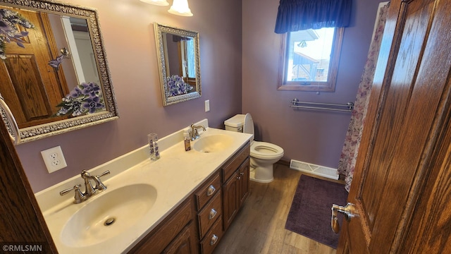 bathroom with a sink, visible vents, toilet, and wood finished floors