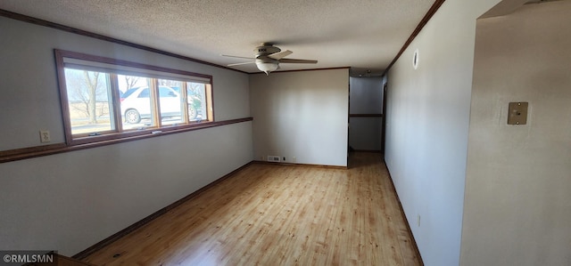 empty room with visible vents, a ceiling fan, a textured ceiling, wood finished floors, and crown molding