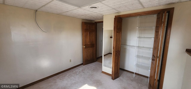 unfurnished bedroom featuring visible vents, baseboards, light carpet, a closet, and a paneled ceiling