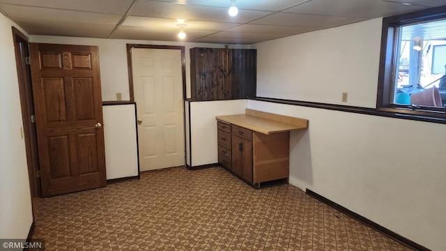 interior space with a drop ceiling and baseboards