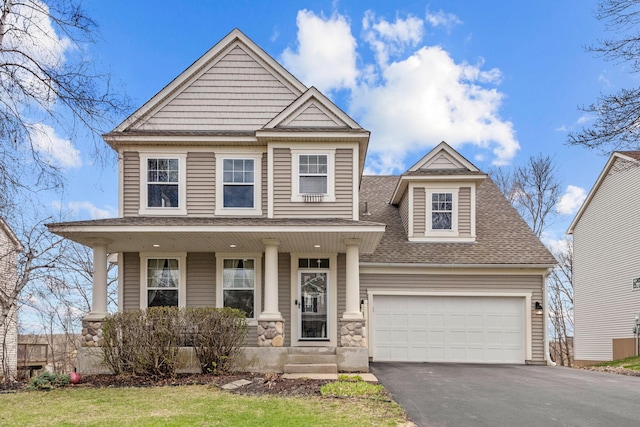 craftsman-style home with driveway, roof with shingles, covered porch, and stone siding