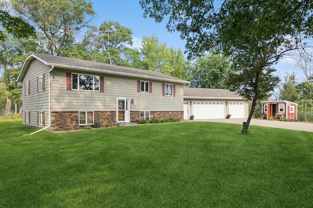 raised ranch with a garage, stone siding, and a front lawn