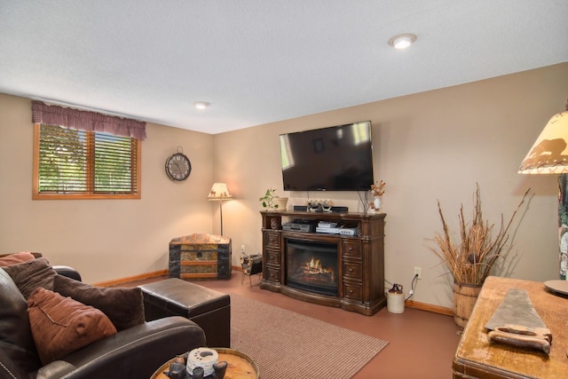 living area with baseboards and a glass covered fireplace