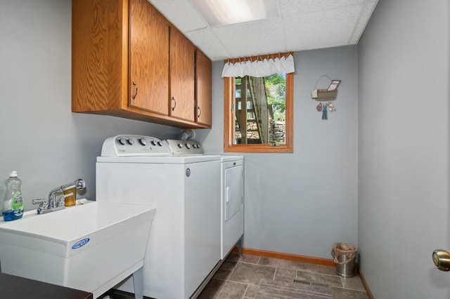 washroom featuring washing machine and clothes dryer, cabinet space, baseboards, and a sink