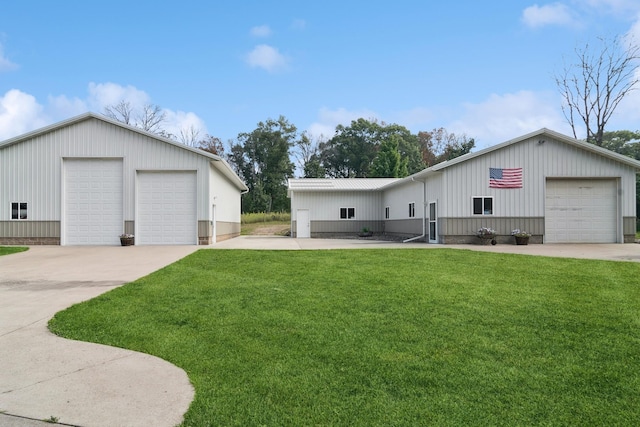 view of front facade with a detached garage, board and batten siding, a front yard, and metal roof