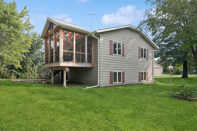 back of property with a sunroom, a yard, stairs, and a detached garage