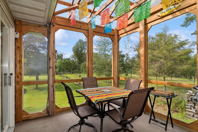 sunroom / solarium featuring carpet and view of wooded area