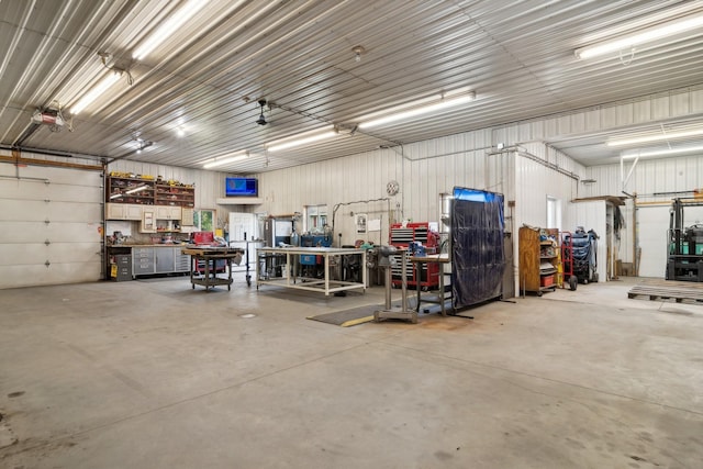 garage with a workshop area, a garage door opener, and metal wall