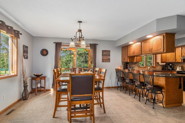 dining space with plenty of natural light, light tile patterned floors, baseboards, a chandelier, and a textured ceiling