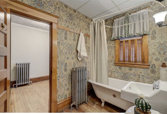 full bathroom with wallpapered walls, radiator heating unit, and hardwood / wood-style floors