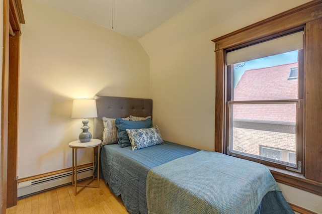 bedroom featuring a baseboard heating unit, vaulted ceiling, and light wood finished floors