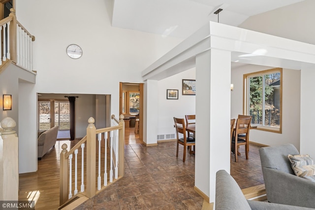 interior space featuring an upstairs landing, visible vents, a healthy amount of sunlight, and baseboards