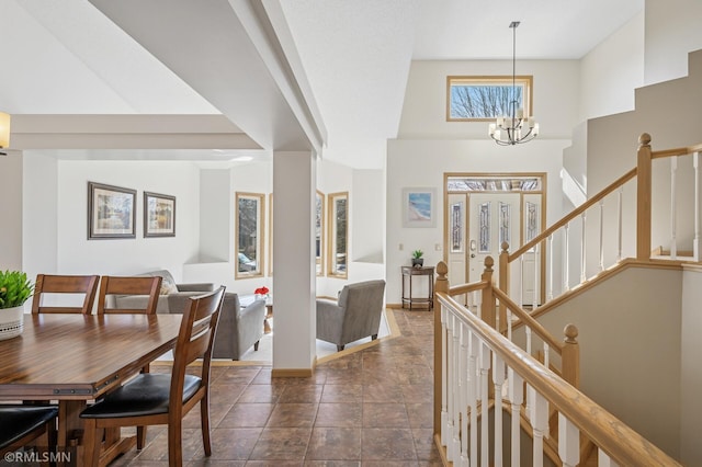 entryway with stairway, a high ceiling, a notable chandelier, and baseboards