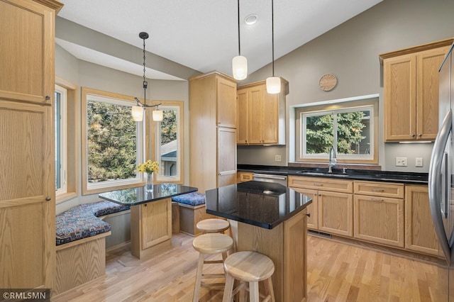 kitchen featuring a sink, a kitchen island, light wood-style floors, and vaulted ceiling