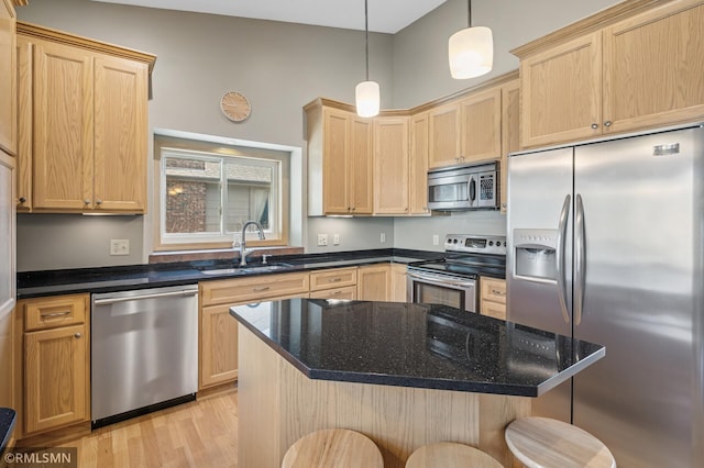 kitchen featuring light brown cabinets, a breakfast bar area, light wood-type flooring, stainless steel appliances, and a sink