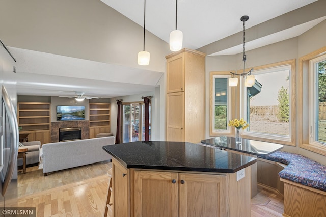 kitchen featuring light wood finished floors, a kitchen island, lofted ceiling, ceiling fan, and light brown cabinetry