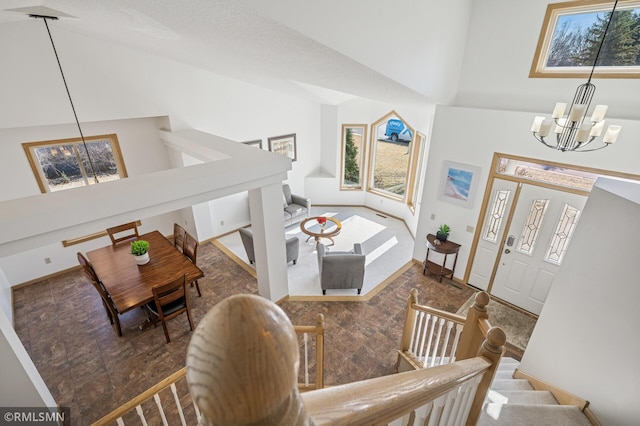 foyer with baseboards, high vaulted ceiling, stairs, and an inviting chandelier