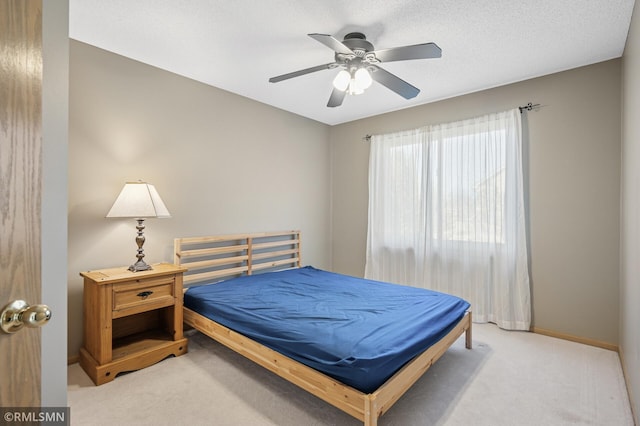 carpeted bedroom with ceiling fan, baseboards, and a textured ceiling