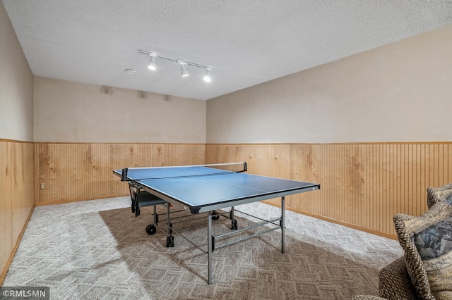 game room featuring wainscoting, wood walls, a textured ceiling, and carpet