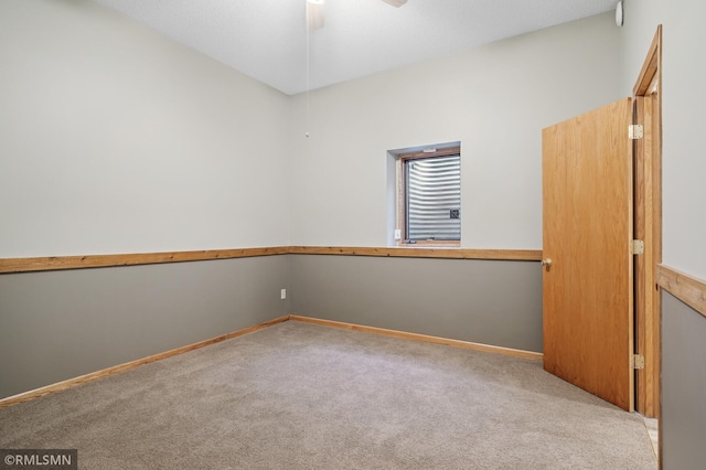 spare room featuring a ceiling fan, carpet, and baseboards