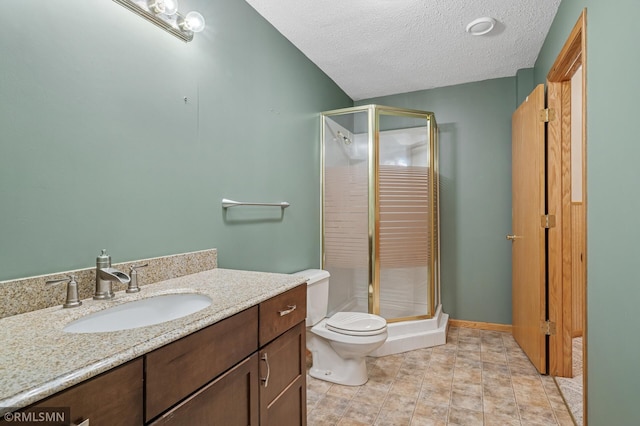 full bath with vanity, toilet, a shower stall, and a textured ceiling