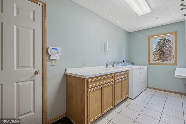 laundry room featuring light tile patterned floors, baseboards, cabinet space, a textured ceiling, and washing machine and dryer