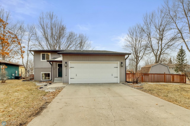 view of front of property featuring an attached garage, driveway, and fence