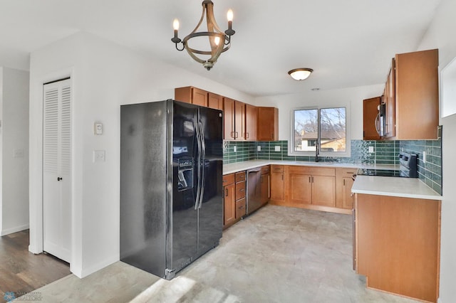 kitchen with brown cabinetry, a sink, light countertops, appliances with stainless steel finishes, and tasteful backsplash