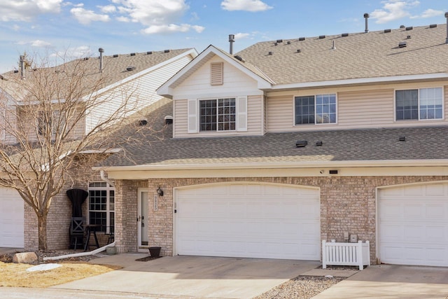 townhome / multi-family property with brick siding, a shingled roof, and a garage