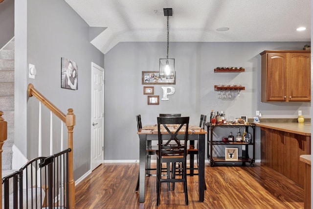 dining area featuring dark wood-type flooring, baseboards, stairs, vaulted ceiling, and a textured ceiling