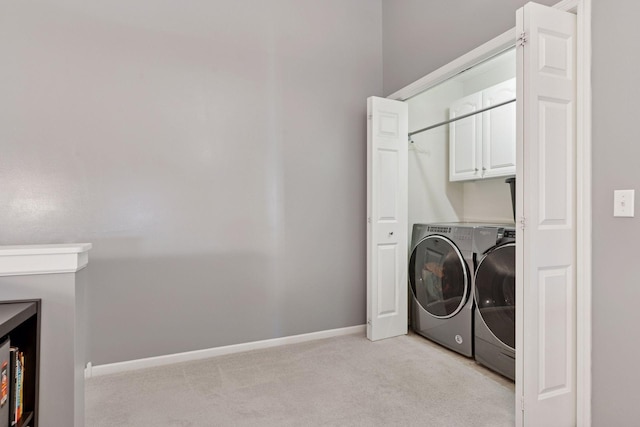 laundry area with washing machine and dryer, cabinet space, light colored carpet, and baseboards