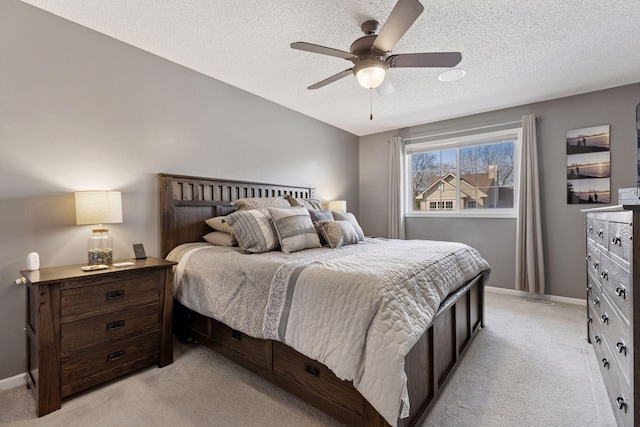 bedroom featuring light colored carpet, a textured ceiling, baseboards, and a ceiling fan