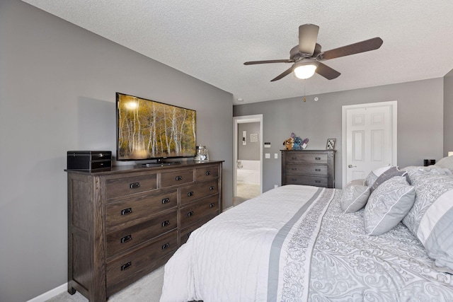 bedroom with baseboards, ensuite bath, ceiling fan, a textured ceiling, and light carpet