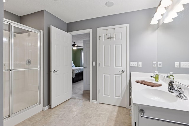 full bath with a stall shower, a sink, a textured ceiling, ensuite bath, and double vanity