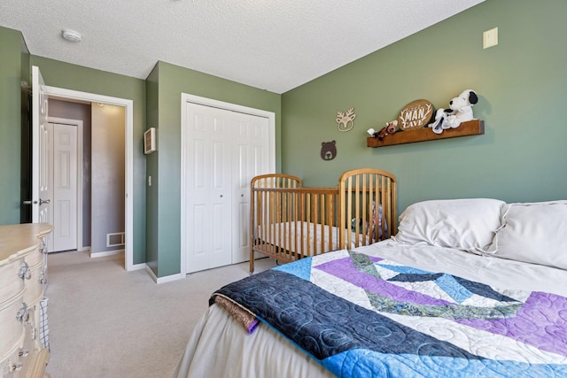 bedroom featuring light carpet, a textured ceiling, baseboards, and a closet