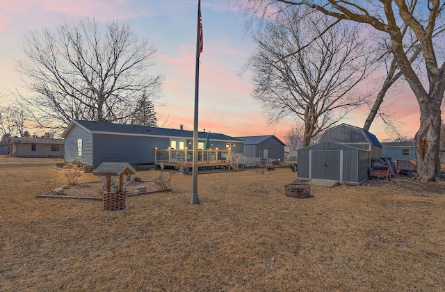 back of property at dusk featuring an outdoor structure, a deck, and a shed