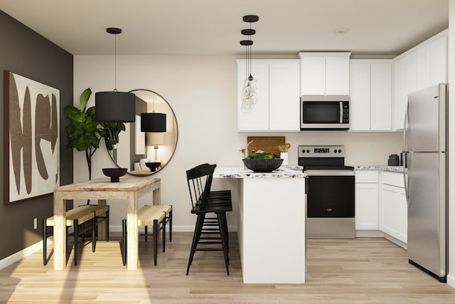 kitchen with white cabinetry, light wood-style flooring, a kitchen bar, and appliances with stainless steel finishes