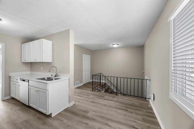 kitchen featuring visible vents, dishwasher, light wood-type flooring, and a sink