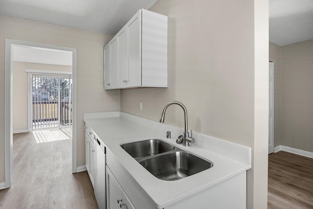 kitchen featuring a textured ceiling, wood finished floors, light countertops, and a sink