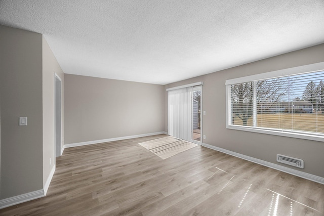 spare room with wood finished floors, baseboards, and a wealth of natural light