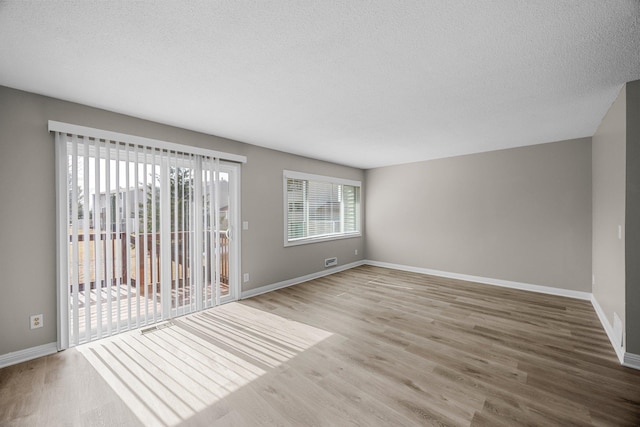 spare room featuring a textured ceiling, baseboards, and wood finished floors