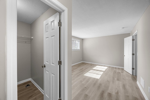 interior space with visible vents, baseboards, a textured ceiling, and wood finished floors