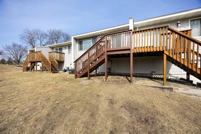 back of house with a deck, stairs, and a yard