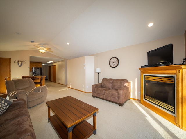 living area with a ceiling fan, baseboards, vaulted ceiling, light carpet, and a glass covered fireplace