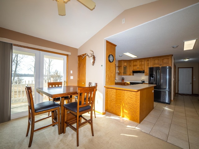 dining space with lofted ceiling, light colored carpet, light tile patterned flooring, and a ceiling fan